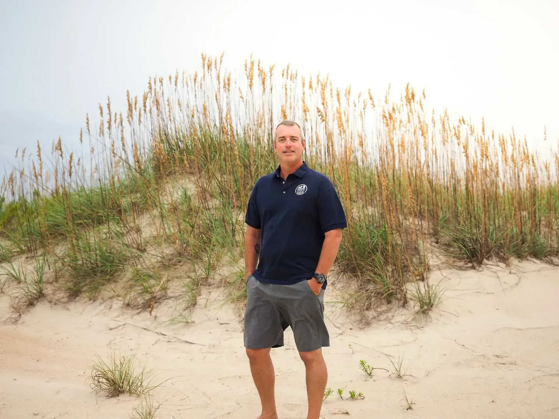 Coastal owner Chad Davis standing among the beach dunes in Virginia Beach
